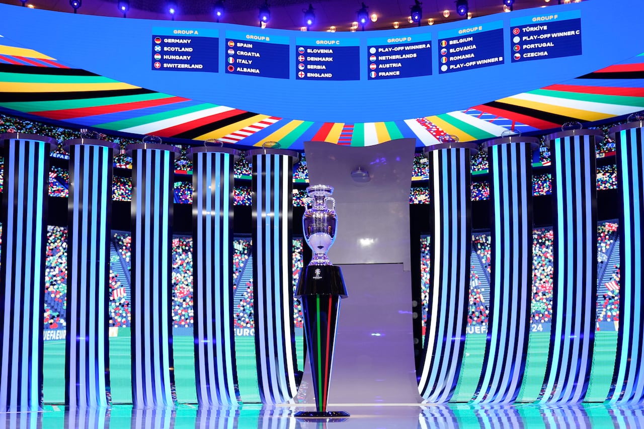 El trofeo colocado frente a un marcador que muestra el sorteo final, excepto los ganadores de los play-offs, después del sorteo de la final del torneo de fútbol UEFA Euro 2024 en Hamburgo, Alemania, el sábado 2 de diciembre de 2023. (Foto AP/Martin Meissner )