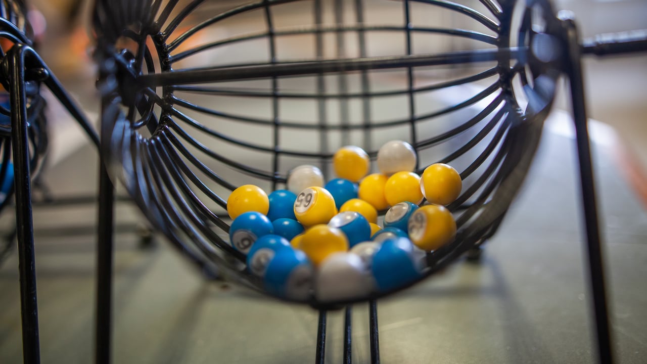 Cette photographie présente des billes de loto dans une structure en métal servant à mélanger le tout.