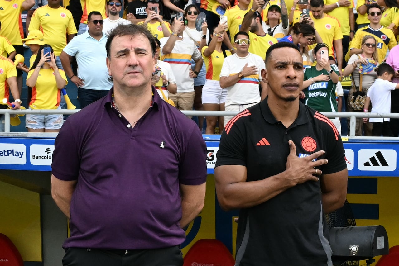 Colombia's Argentine head coach Nestor Lorenzo (L) and assistant coach Luis Amaranto Perea listen to the anthem before the 2026 FIFA World Cup South American qualifiers football match between Colombia and Peru, at the Metropolitano Roberto Melendez stadium in Barranquilla, Colombia, on June 6, 2025. (Photo by Luis ACOSTA / AFP)