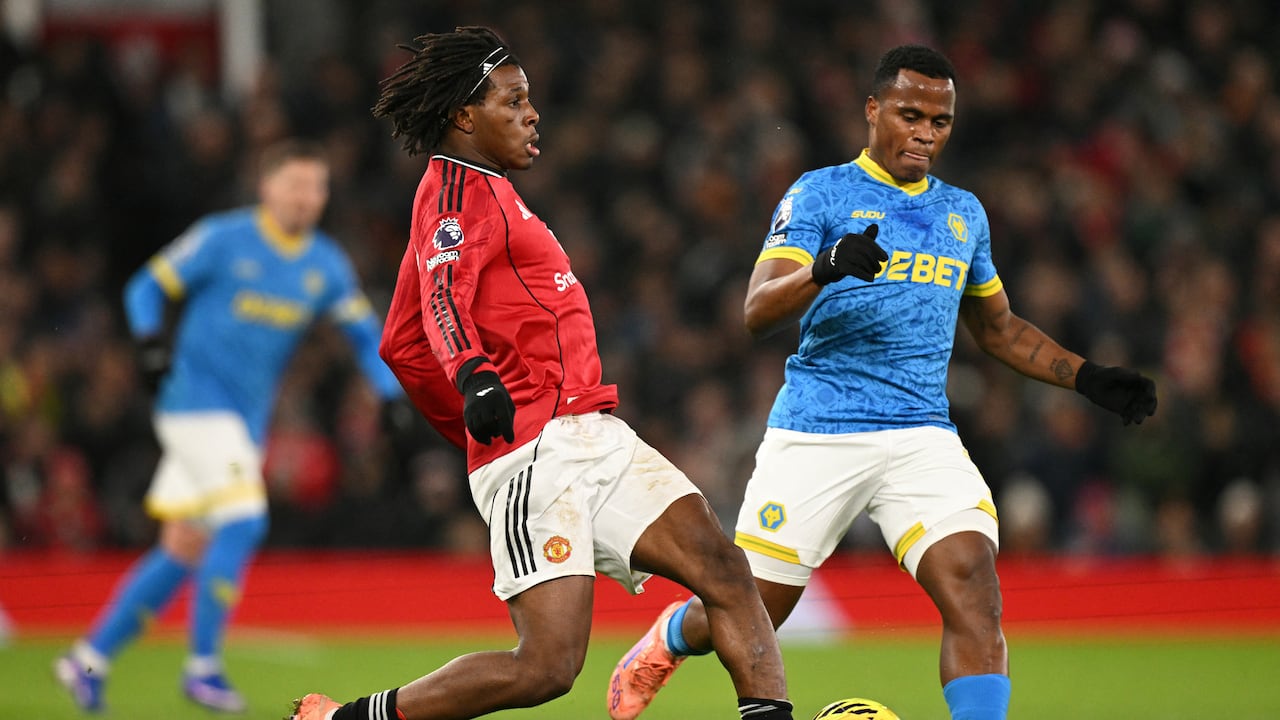 El defensa danés #13 del Manchester United, Patrick Dorgu (centro), juega el balón bajo la presión del delantero colombiano #10 del Wolverhampton Wanderers, Jhon Arias (derecha), durante el partido de la Premier League inglesa entre el Manchester United y el Wolverhampton Wanderers en Old Trafford en Manchester, noroeste de Inglaterra, el 30 de diciembre de 2025. (Foto de Oli SCARFF / AFP)