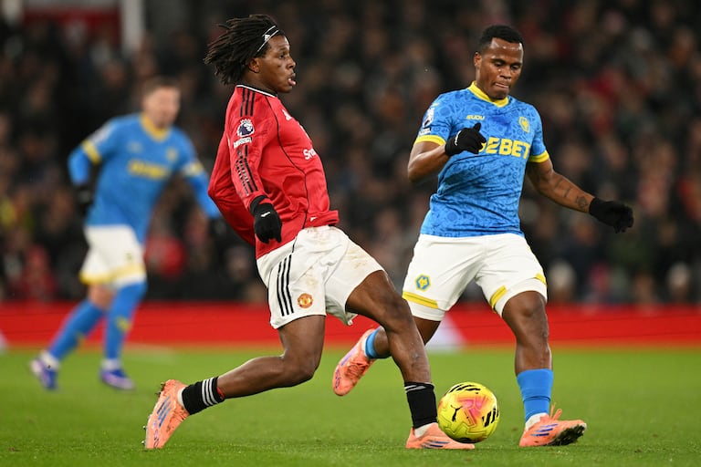 El defensa danés #13 del Manchester United, Patrick Dorgu (centro), juega el balón bajo la presión del delantero colombiano #10 del Wolverhampton Wanderers, Jhon Arias (derecha), durante el partido de la Premier League inglesa entre el Manchester United y el Wolverhampton Wanderers en Old Trafford en Manchester, noroeste de Inglaterra, el 30 de diciembre de 2025. (Foto de Oli SCARFF / AFP)