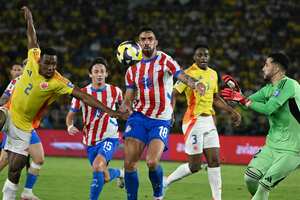 El delantero de Paraguay, Gabriel Ávalos, intenta cabecera el balón, ante la aparición del colombiano,  Carlos Cuesta, en el partido de las Eliminatorias Sudamericanas 2026, en Barranquilla. (Foto  Luis ACOSTA / AFP)