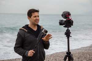 Blogger haciendo video sobre cámaras y fotografías en la playa.