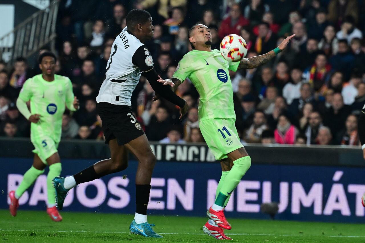 El delantero brasileño del Barcelona #11 Raphinha (R) controla el balón desafiado por el defensor español del Valencia #03 Cristhian Mosquera.