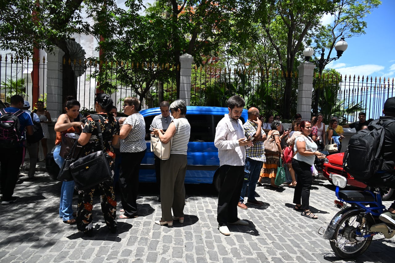 Trabajadores revisan sus teléfonos celulares tras un temblor provocado por un terremoto de magnitud 6,1 en La Habana, el 8 de junio de 2026. Un fuerte sismo sacudió la costa occidental de Cuba el 8 de junio de 2026. Periodistas de AFP en La Habana informaron de 20 segundos de temblor que obligaron a los cubanos a salir de los edificios a las calles. El Servicio Geológico de Estados Unidos informó que el terremoto tuvo una magnitud de 6.1 y se produjo a unos 100 kilómetros (62 millas) de la punta occidental de la isla. (Foto de YAMIL LAGE / AFP)