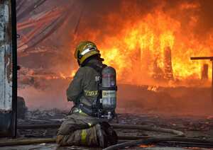 Un bombero del Cuerpo Voluntario de Bomberos de Cali trabaja en la emergencia que se presentó este viernes por el incendio de una bodega en el barrio Olaya Herrera en el norte de Cali. Foto: Raúl Palacios / El País