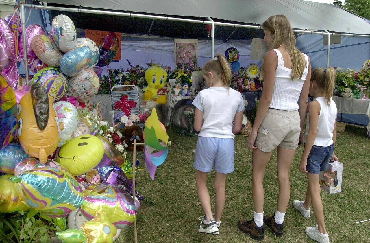 La gente mira el monumento improvisado frente a la casa de Cassandra ''Casey'' Williamson, 29 de julio de 2002, en Valley Park, Missouri. Johnny Johnson, quien secuestró y mató a golpes a una niña de 6 años
