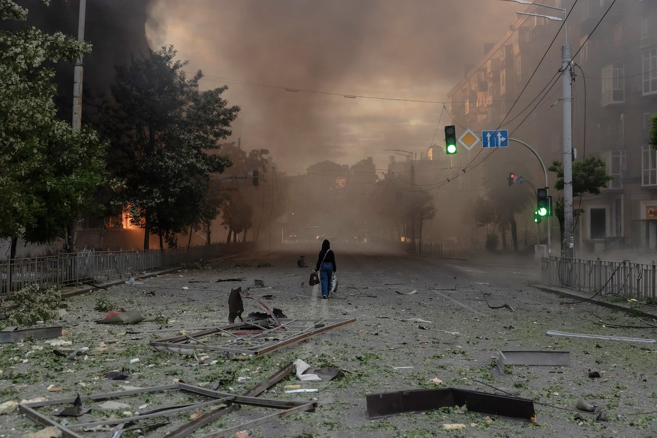 Una mujer camina por una calle llena de humo junto a edificios gravemente dañados tras los ataques rusos en Kiev el 24 de mayo de 2026, en el contexto de la invasión rusa de Ucrania. Un potente ataque con misiles balísticos sacudió Kiev a primera hora del 24 de mayo, según informaron las autoridades, hiriendo al menos a cinco personas después de que Moscú amenazara con represalias por los ataques en el este de Ucrania, territorio ocupado por Rusia. (Foto de Roman PILIPEY / AFP)