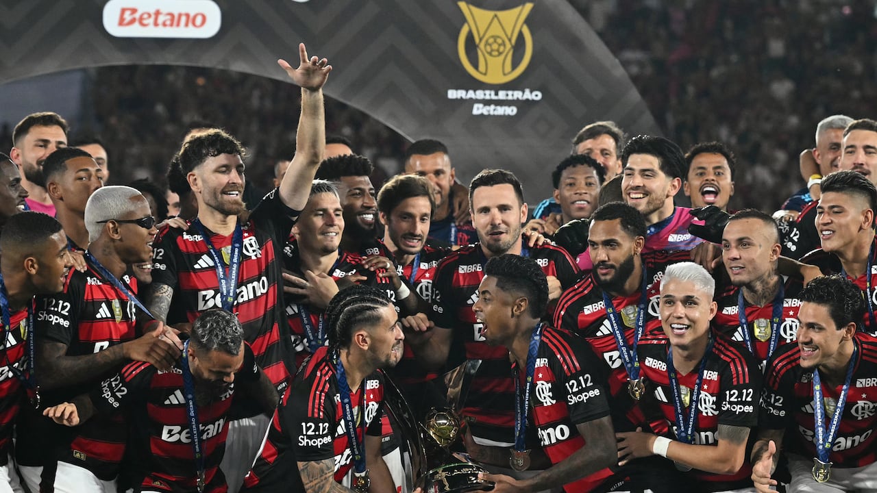 El mediocampista uruguayo del Flamengo #10 Giorgian de Arrascaeta (centro izquierdad) y el delantero #27 Bruno Henrique (centro derecha) levantan el trofeo Brasileirao después de ganar el partido de fútbol Brasileirao Serie A entre Flamengo y Ceará en el estadio Maracaná de Río de Janeiro, Brasil, el 3 de diciembre de 2025. (Foto de Mauro PIMENTEL / AFP)