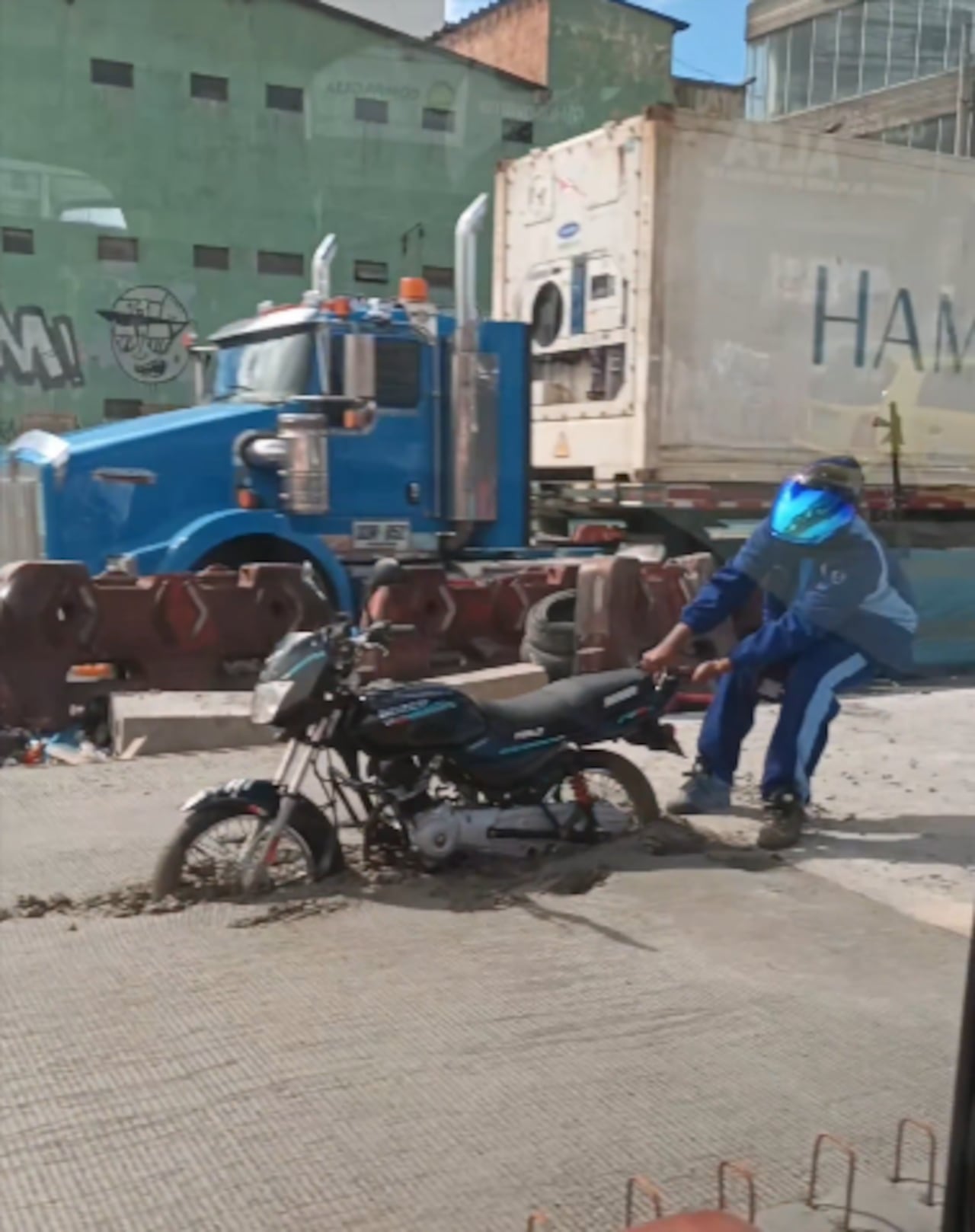 El joven intentaba con todas sus fuerzas sacar la moto del cemento.