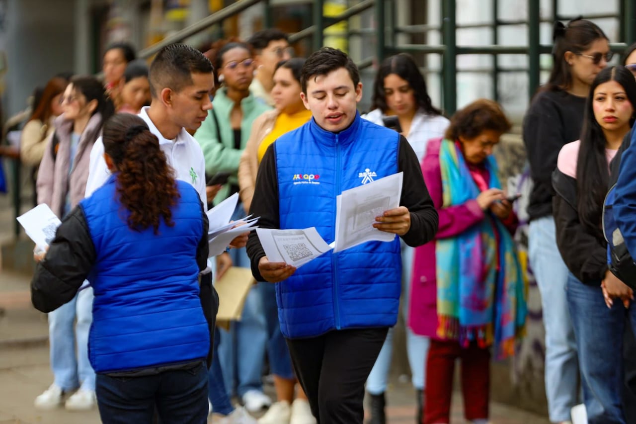Un funcionario del Sena en compañía de personas que buscan empleo, en Bogotá