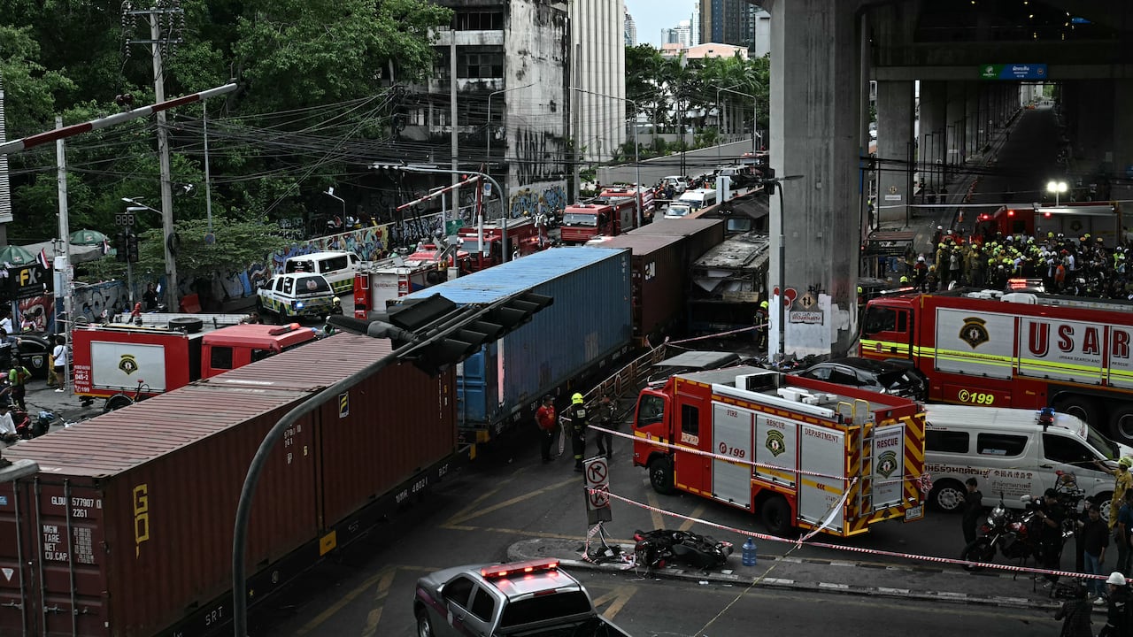 Agentes de policía, rescatistas y bomberos se encuentran en el lugar del accidente donde un tren y un autobús colisionaron bajo la estación de tren del aeropuerto de Makkasan en Bangkok el 16 de mayo de 2026. La colisión entre un tren de carga y un autobús dejó al menos ocho muertos y más de 30 heridos en la capital tailandesa, Bangkok, según informaron los servicios de emergencia. (Foto de Lillian SUWANRUMPHA / AFP)