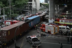Agentes de policía, rescatistas y bomberos se encuentran en el lugar del accidente donde un tren y un autobús colisionaron bajo la estación de tren del aeropuerto de Makkasan en Bangkok el 16 de mayo de 2026. La colisión entre un tren de carga y un autobús dejó al menos ocho muertos y más de 30 heridos en la capital tailandesa, Bangkok, según informaron los servicios de emergencia. (Foto de Lillian SUWANRUMPHA / AFP)