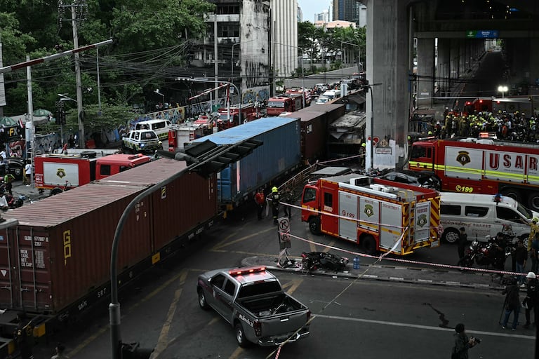 Agentes de policía, rescatistas y bomberos se encuentran en el lugar del accidente donde un tren y un autobús colisionaron bajo la estación de tren del aeropuerto de Makkasan en Bangkok el 16 de mayo de 2026. La colisión entre un tren de carga y un autobús dejó al menos ocho muertos y más de 30 heridos en la capital tailandesa, Bangkok, según informaron los servicios de emergencia. (Foto de Lillian SUWANRUMPHA / AFP)