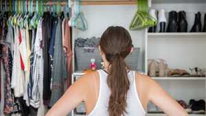 Esta es una joven adulta con las manos en las caderas tratando de decidir qué ponerse de su armario bien organizado.