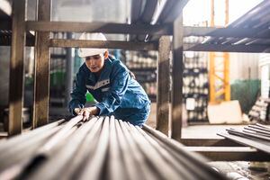Mujer de una fábrica de acero en el trabajo moviendo postes de acero