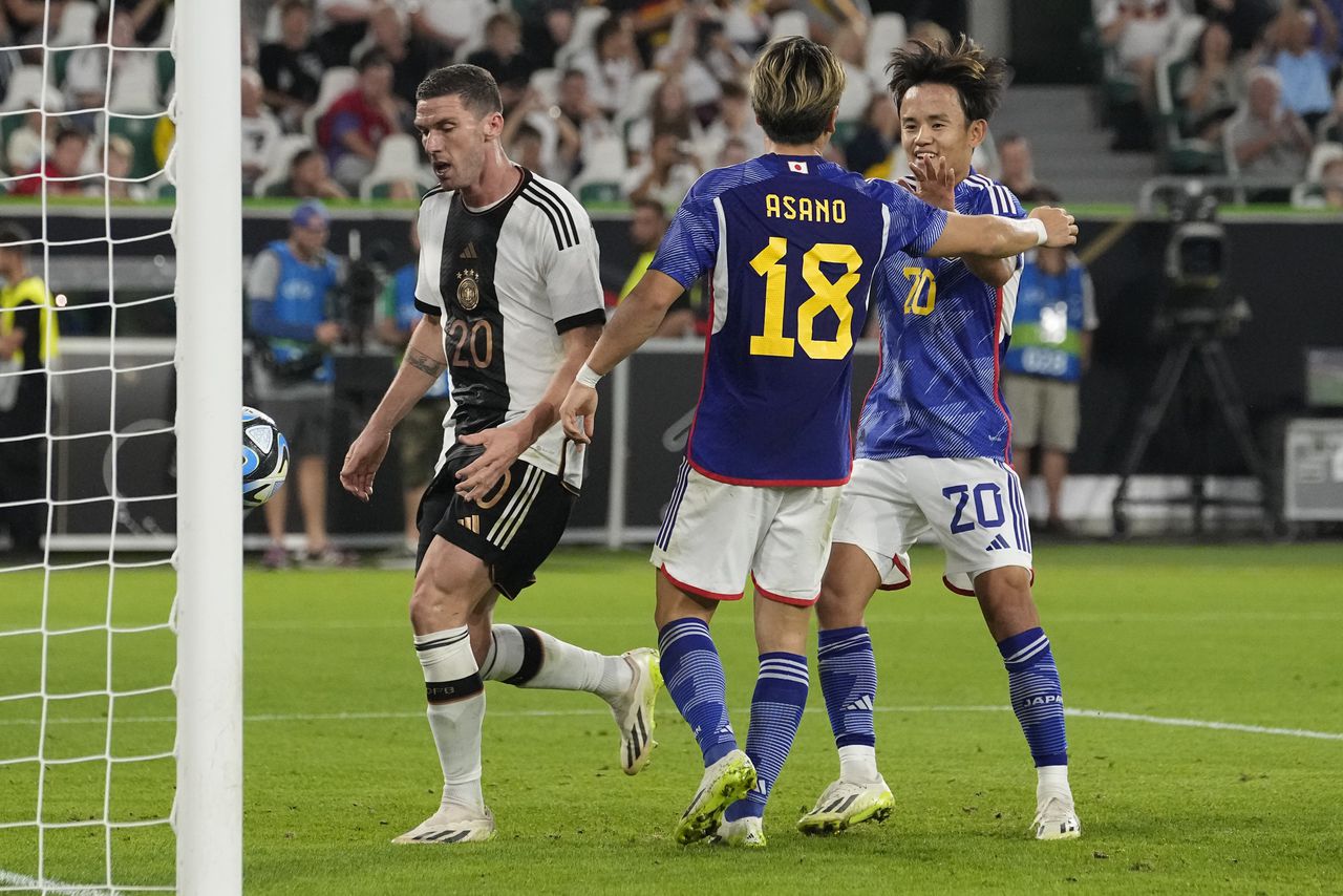 El japonés Takuma Asano, centro, celebra con el japonés Takefusa Kubo, derecha, después de anotar el tercer gol de su equipo durante un partido amistoso de fútbol internacional entre Alemania y Japón en Wolfsburg, Alemania, el sábado 9 de septiembre de 2023. (Foto AP/Martin Meissner)
