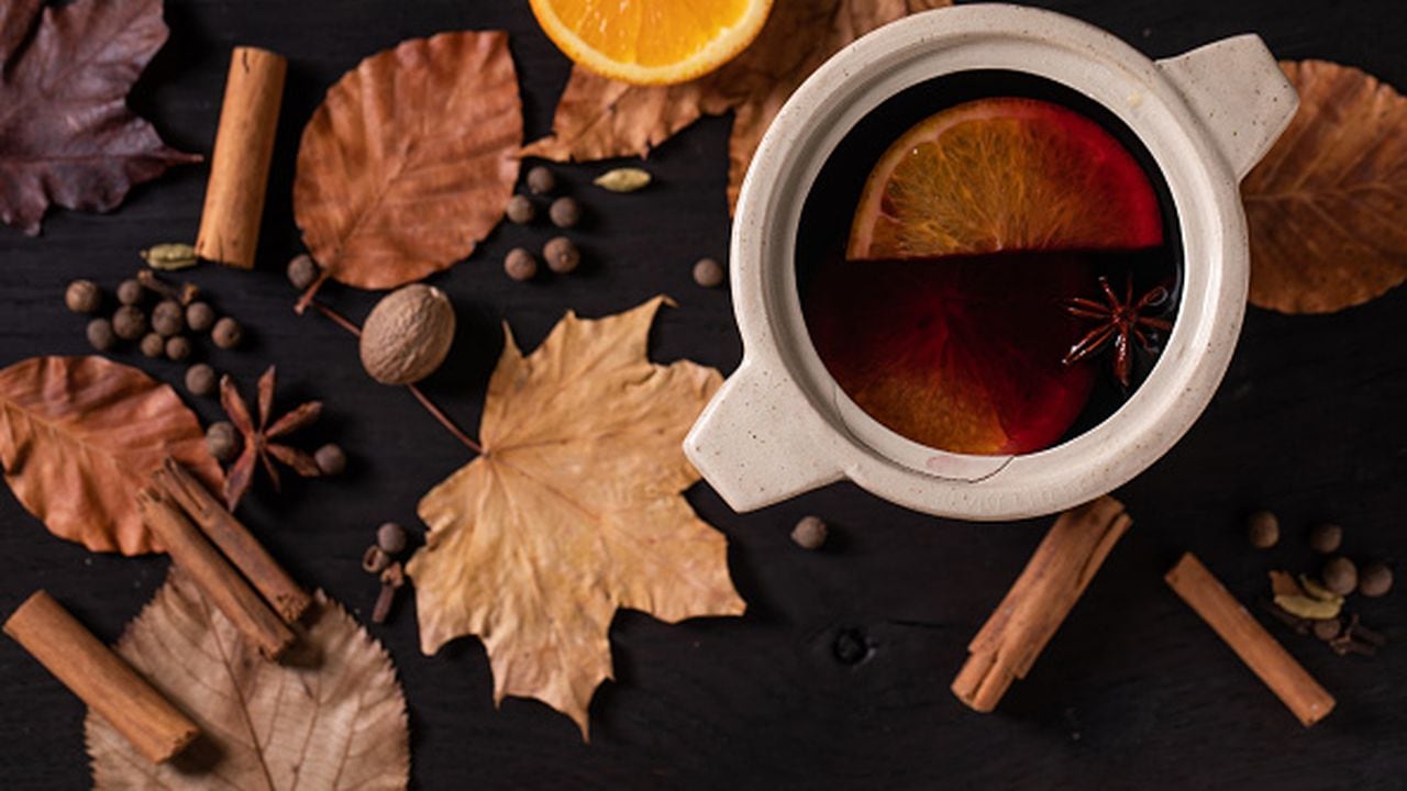 Hot mulled wine in ceramic pot with spices, orange and autumn leaves over black wooden background, Flat lay, Cozy warm alcohol drinks. (Photo by: Natasha Breen/REDA&CO/Universal Images Group via Getty Images)