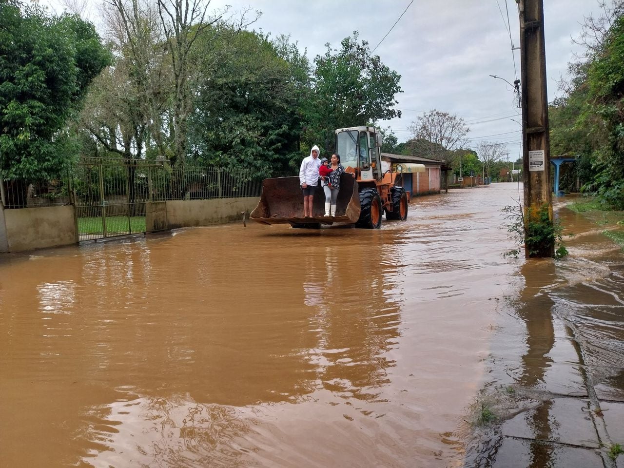 Una familia cruza una calle inundada en un cargador en la ciudad de Novo Hamburgo, estado de Rio Grande do Sul, luego de que un ciclón extratropical azotara la región sur de Brasil, provocando tormentas eléctricas y vendavales, el 17 de junio de 2023.