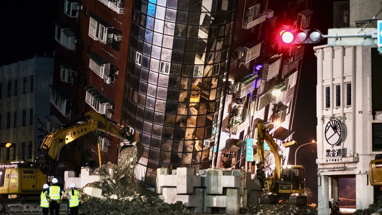 El personal de emergencia se encuentra frente a un edificio parcialmente derrumbado que se inclina sobre una calle en Hualien el 3 de abril de 2024, después de que un gran terremoto azotara el este de Taiwán (Foto de Sam Yeh / AFP)