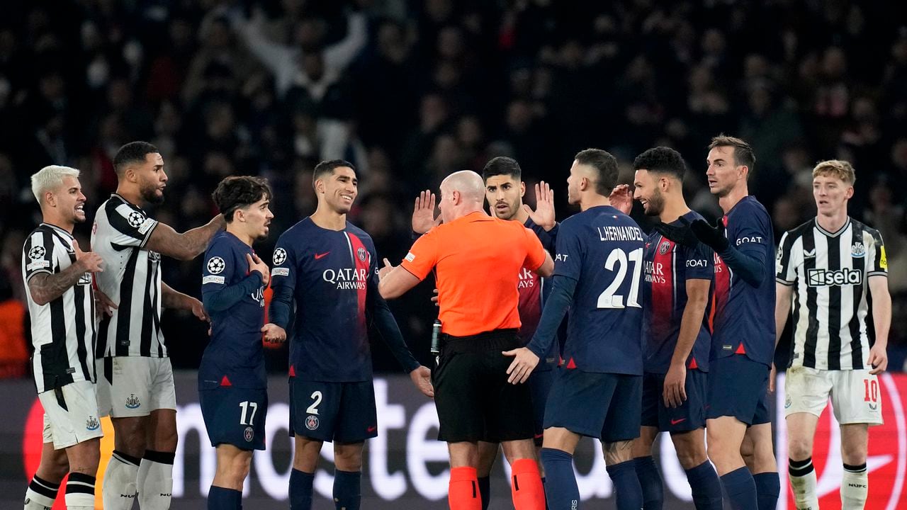 Los jugadores del PSG rodean al árbitro Szymon Marciniak al reclamar un penal en el partido contra Newcastle en la Liga de Campeones, el martes 28 de noviembre de 2023, en París. (AP Foto/Christophe Ena)
