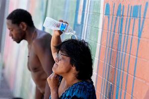 FILE - People, who are homeless, try to cool down with chilled water outside the Justa Center, a day center for homeless people 55 years and older, July 14, 2023, in downtown Phoenix. Homeless people are among the people most likely to die in the extreme heat in Phoenix. (AP Photo/Matt York, File)