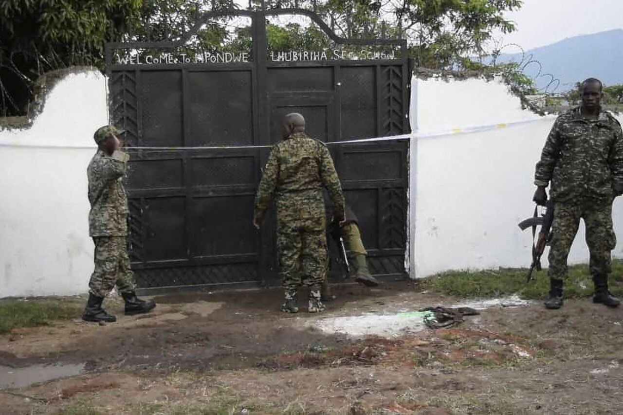 Las fuerzas de seguridad de Uganda se ven de pie en las instalaciones de un ataque en Mpondwe, Uganda, el 17 de junio de 2023 en la escuela secundaria Mpondwe Lhubiriha.