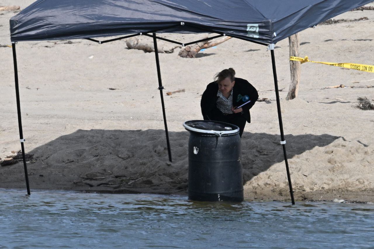 An official stands next to a barrel where a body was discovered in Malibu Lagoon State Beach, California on July 31, 2023. A body stuffed in a barrel was discovered July 31, 2023 on Malibu Beach, a swanky Californian hotspot beloved by the rich and famous, police said. Reports said the man's corpse was crammed into a 55-gallon drum when it was discovered by maintenance workers. (Photo by Robyn Beck / AFP)