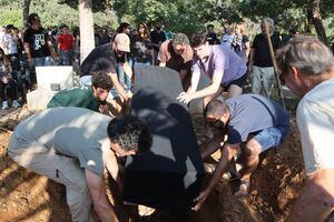 Los dolientes colocan el ataúd de Tom Godo, muerto durante el ataque de militantes palestinos de Hamas al Kibbutz Kisuffim la semana pasada, durante su funeral en el Kibbutz Naan, cerca de Tel Aviv, el 13 de octubre de 2023. Miles de personas, tanto israelíes como palestinos, han muerto desde octubre.
