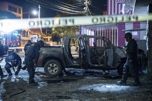 La policía inspecciona una camioneta que explotó afuera de una oficina utilizada por el Servicio Nacional de Atención a Personas Privadas de Libertad que administra el sistema penitenciario en Quito, Ecuador, la madrugada del jueves 31 de agosto de 2023. (AP Foto/Carlos Noriega)
