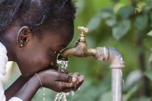 Niña africana bebiendo agua limpia de un grifo. Manos ahuecadas de un niño africano con agua saliendo de un grifo en las calles de la ciudad africana de Bamako, Malí.